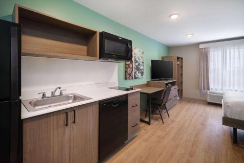 a kitchen with a sink and a table in a room at ECHO Suites Extended Stay by Wyndham Indianapolis AmeriPlex in Indianapolis