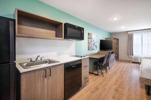 a kitchen with a sink and a table with chairs at ECHO Suites Extended Stay by Wyndham Indianapolis AmeriPlex in Indianapolis
