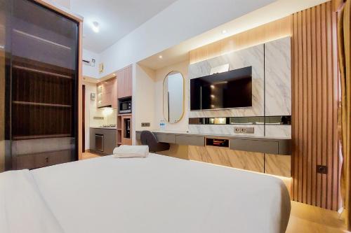 sypialnia z dużym łóżkiem i telewizorem w obiekcie Simply Look and Comfort Studio Room at Casa de Parco Apartment By Travelio w mieście Tangerang
