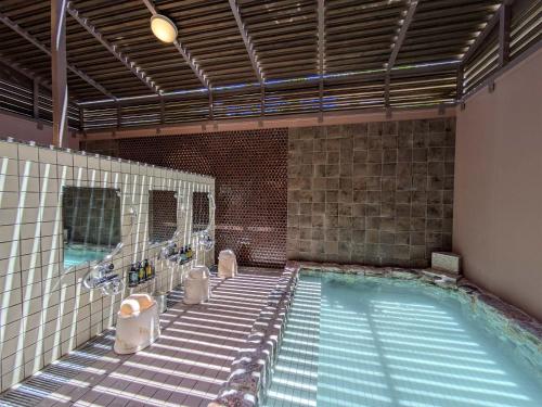a bathroom with a swimming pool with sinks and toilets at Route Inn Grantia Ishigaki in Ishigaki Island