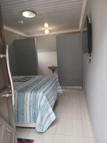 a small bedroom with a bed and a tiled floor at Pythons Guest Lodge in Rustenburg
