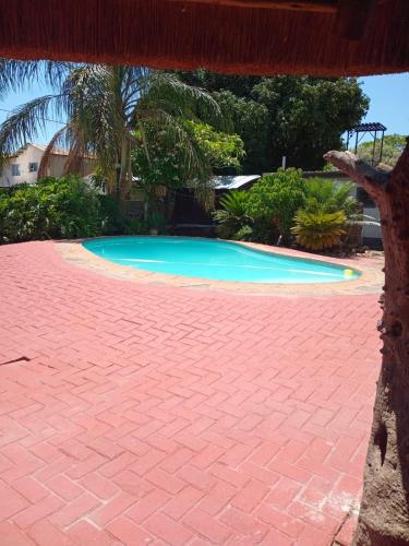 a swimming pool with a red brick walkway around it at Pythons Guest Lodge in Rustenburg