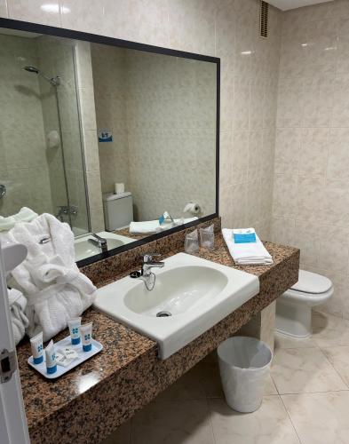 a bathroom with a sink and a mirror and a toilet at Complejo BLUESEA Puerto Resort compuesto por Hotel Canarife y Bonanza Palace in Puerto de la Cruz