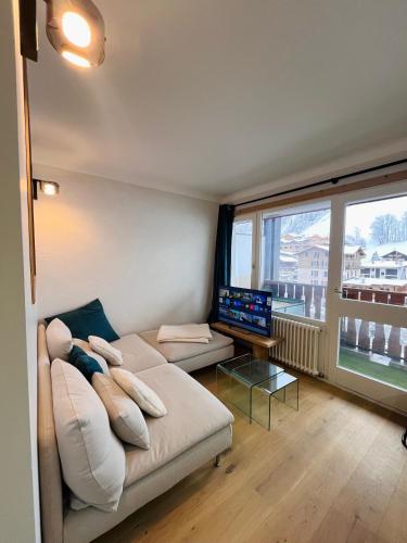 un salon avec un canapé et une télévision à écran plat dans l'établissement Appartement de Montagne au Centre de la Clusaz, à La Clusaz