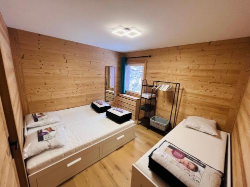 - une chambre avec 2 lits dans un mur en bois dans l'établissement Appartement de Montagne au Centre de la Clusaz, à La Clusaz