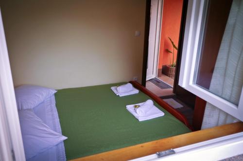 a small room with a green bed with towels on it at Garden House in Matulji