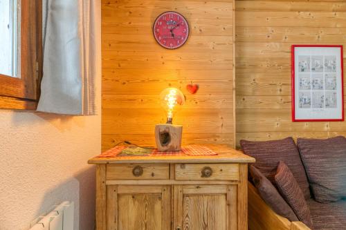 a light on a wooden table with a clock on a wall at Granges 32 - Beau Duplex Spacieux in Villard-Reculas
