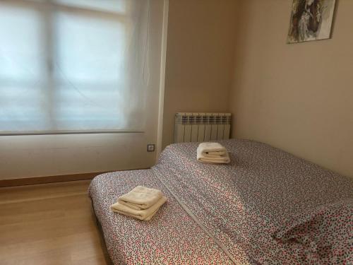 a bedroom with a bed with two towels on it at Apartamentos El Espolón in Logroño
