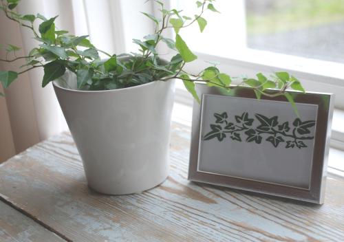 a plant in a white vase next to a picture at Villa Vilan - Countryside Lodging in Skillingaryd