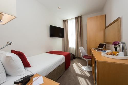 a hotel room with a bed and a desk with a laptop at Yak & Yeti in Shrewsbury