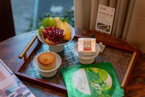 a table with a tray with desserts and fruit on it at 指云公馆Lijiang Mufu Royal Garden Resort半山观景民宿 in Lijiang
