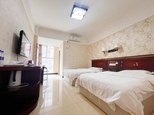 a hotel room with two beds and a television at MAXHILL inn悦季时光酒店 in Jinghong