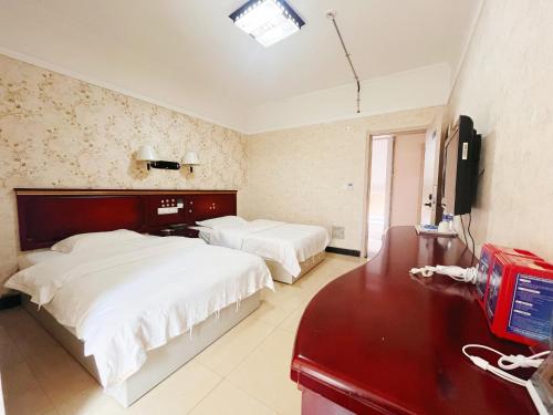 a bedroom with two beds and a desk and a television at MAXHILL inn悦季时光酒店 in Jinghong