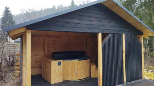 a large wooden dog house with a black roof at Domki w Dolinie Wieżycy in Szymbark