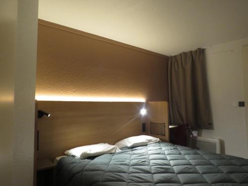 a bedroom with a bed with a light above it at HOTEL PREMIERE CLASSE Rouen Sud Oissel in Saint-Étienne-du-Rouvray