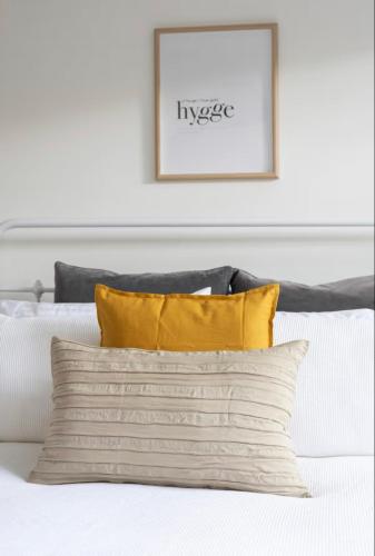 a white bed with yellow pillows and a picture on the wall at Designer townhome adjacent to East Brunswick Village 2min to tram plus private parking in Melbourne