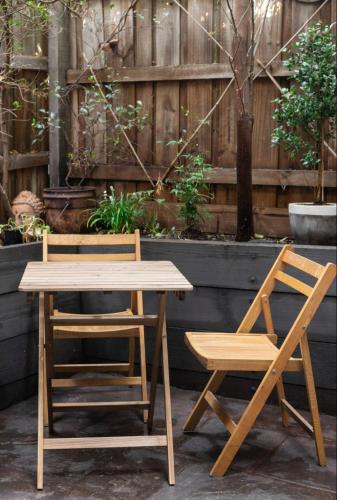 a wooden table and two chairs next to a fence at Designer townhome adjacent to East Brunswick Village 2min to tram plus private parking in Melbourne
