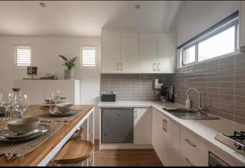 a kitchen with white cabinets and a wooden counter top at Designer townhome adjacent to East Brunswick Village 2min to tram plus private parking in Melbourne