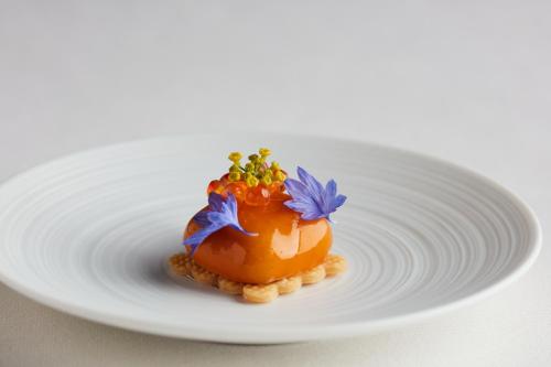 a white plate with an orange dessert with flowers on it at Lympstone Manor Hotel Restaurant & Vineyard - Relais & Chateaux in Exmouth