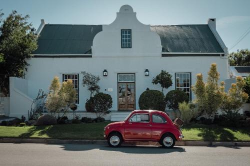 an old red car parked in front of a house at De Bergkant in Prince Albert