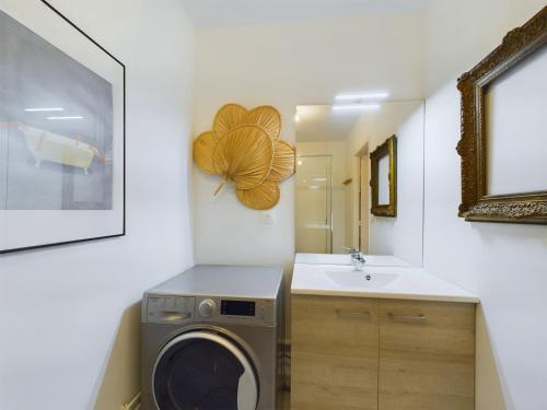 une salle de bain avec une machine à laver et un lavabo dans l'établissement Au pied de la plage - Appartement pour 2, à Pléneuf-Val-André