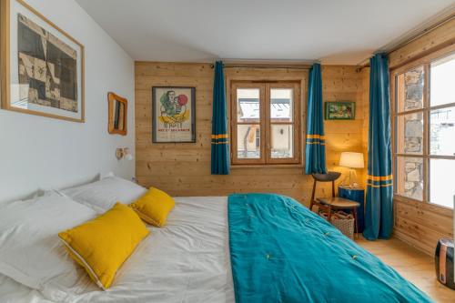 a bedroom with a large bed with blue curtains at Klochette - Charme Et Famille in Villard-Reculas