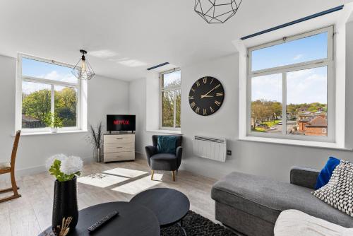 a white living room with a clock on the wall at 30 percent off! Beautiful Apartment in Dewsbury - Sleeps 6 in Leeds