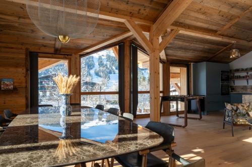 une salle à manger avec une table en verre et une grande fenêtre dans l'établissement Chalet Le Grizzly, aux Gets