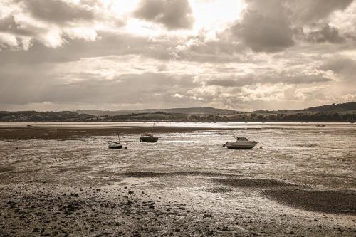 three boats sitting in the water on a beach at Lympstone Manor Hotel Restaurant & Vineyard - Relais & Chateaux in Exmouth