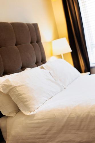 a bed with a brown headboard and white pillows at The Picasso - Trendy 2 bd Ap- Dublin 4 - Super Fast WIFI in Dublin