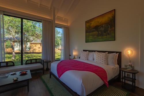 a bedroom with a large bed and large windows at The Postcard in the Durrung Tea Estate, Assam in Tezpur
