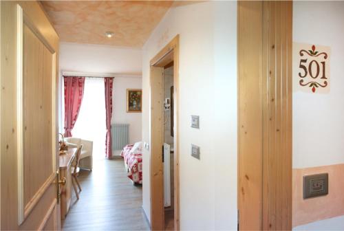 a hallway with a room with a bed and a window at Al Posta Hotel 1899 in Baselga di Pinè