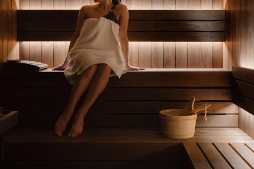 a woman is sitting in a sauna at Hôtel Balzac Paris & Spa Ikoï in Paris