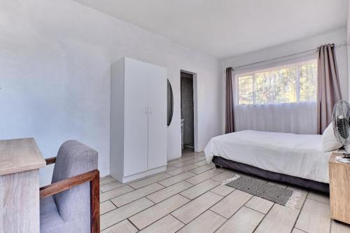 a bedroom with a bed and a desk and a window at Waterfall Bed & Breakfast in Midrand