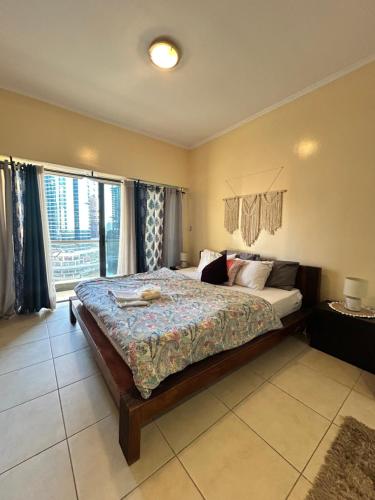 a bedroom with a bed and a large window at Click Stay - JLT - Studio & Balcony Lakes view Entire Apartment -RA in Dubai