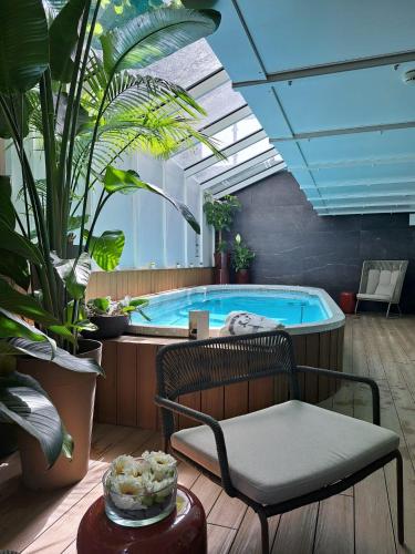 - une piscine dans une pièce avec des plantes et une chaise dans l'établissement Hôtel Garrigae Villa La Florangerie - SPA & Piscine, à Strasbourg
