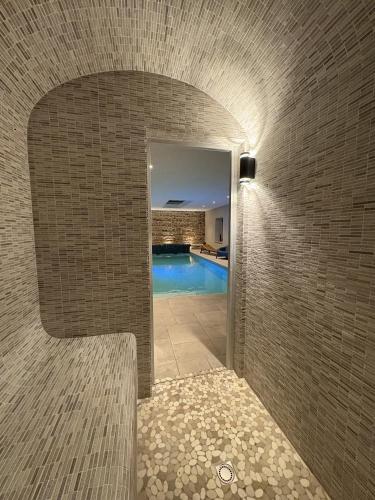 un couloir en briques avec une piscine dans une maison dans l'établissement Les Villas d Onalou Kergastel, à Penvénan