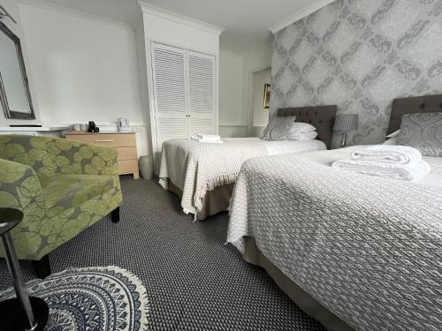 a hotel room with two beds and a chair at The Paddocks Hotel in Symonds Yat