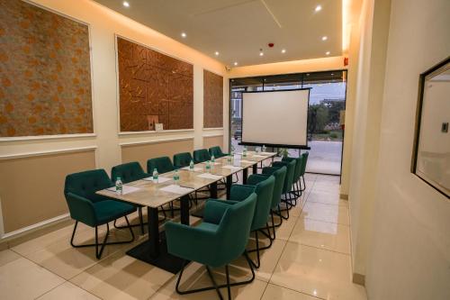 a conference room with a long table and green chairs at ACR Luxury Hotel in Mohali