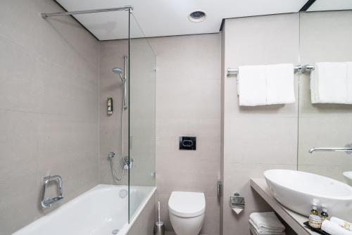 a bathroom with a shower and a toilet and a sink at Steigenberger Hotel Bielefelder Hof in Bielefeld
