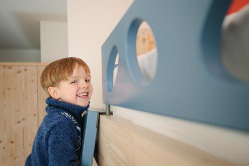 a little boy is standing next to a table at Randolins Familienresort in St. Moritz