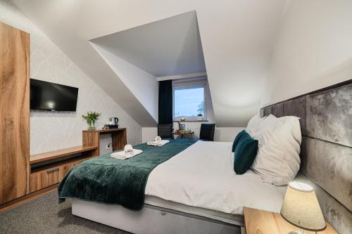 a bedroom with a large bed and a television at GOŚCINIEC ZACISZE - pokoje & restauracja blisko A2 Dąbie - Uniejów in Dąbie