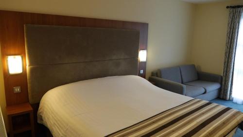 a hotel room with a bed and a chair at The Big Blue Hotel - Blackpool Pleasure Beach in Blackpool