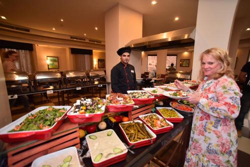 a woman standing in front of a buffet of food at La Maison Hotel in Wadi Musa