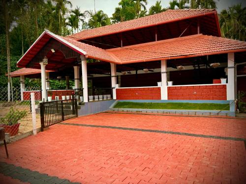a building with a red roof and a red brick driveway at Haveli Holiday Home in Mudigere