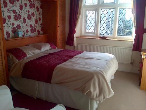 a bedroom with a large bed and two windows at Lewinsdale Lodge in Weston-super-Mare