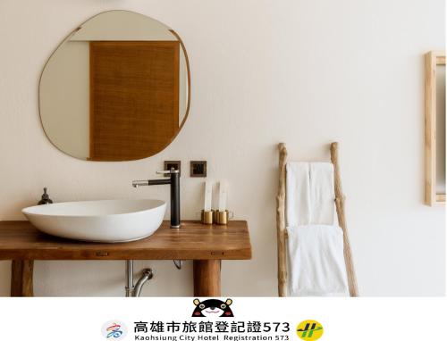 a bathroom with a sink and a mirror on a table at Just Inn Kaohsiung in Kaohsiung