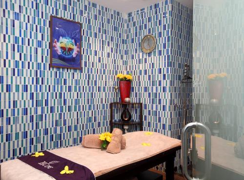 baño con paredes de azulejos azules y mesa con flores en Mena Hotel Al Jubail, en Al Jubail