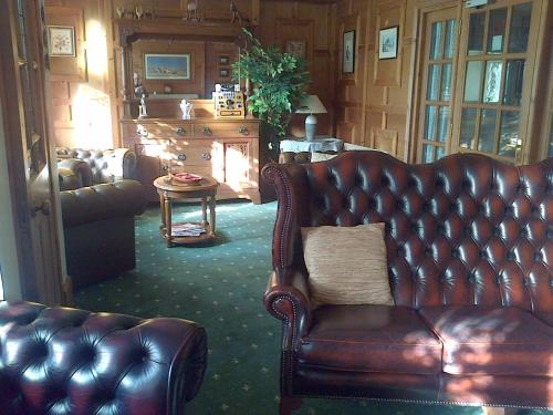 a living room with a leather couch and a table at Lewinsdale Lodge in Weston-super-Mare