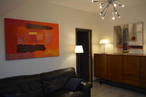 a living room with a couch and a painting on the wall at Appartement-terrasse parking privé Meublé de Tourisme 4 étoiles in Belfort